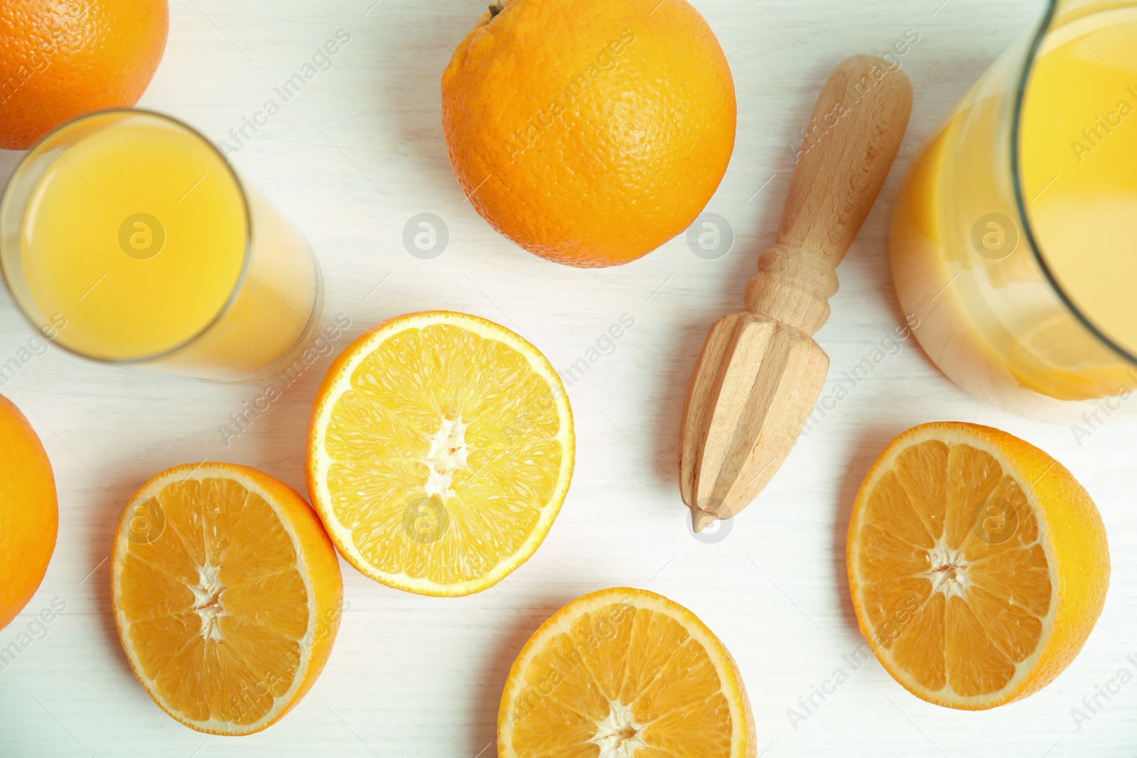 Photo of Fresh ripe oranges, juice and reamer on white wooden table, flat lay