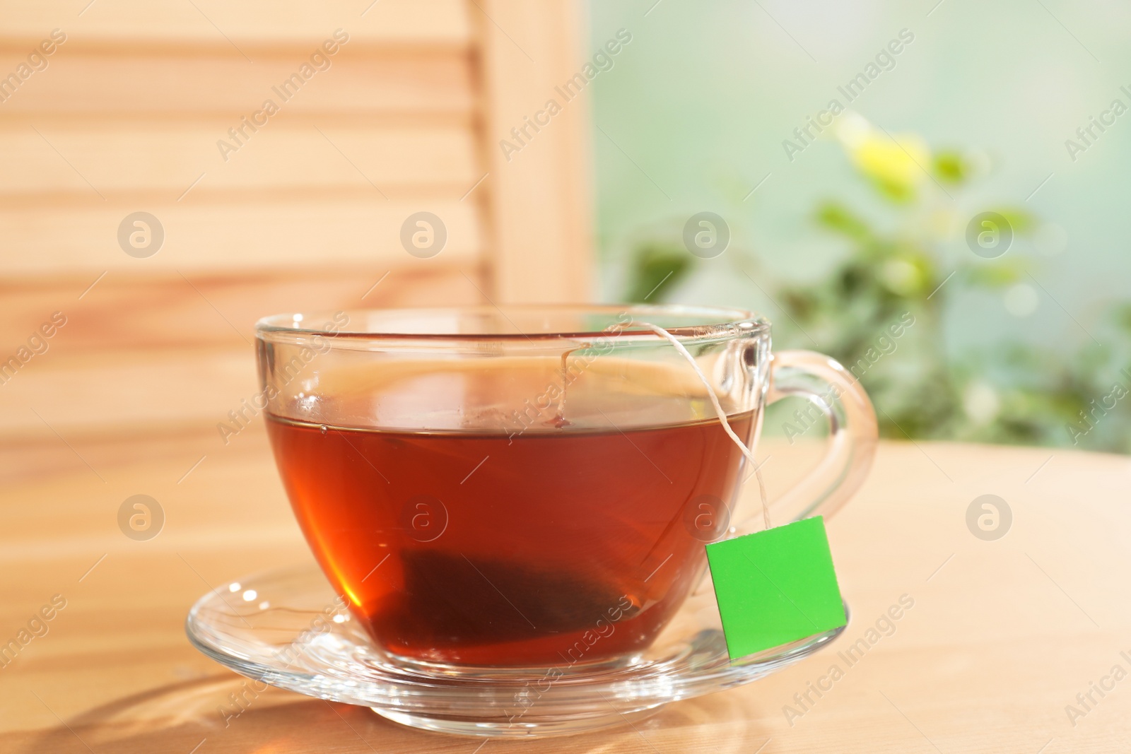 Photo of Brewing tea with bag in cup on table