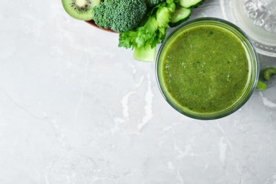 Photo of Delicious green juice and fresh ingredients on grey marble table, flat lay. Space for text