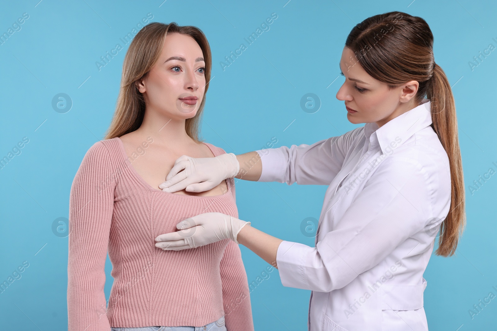 Photo of Mammologist checking woman's breast on light blue background
