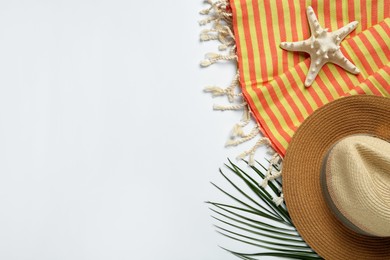 Photo of Beach towel and straw hat on light background, flat lay. Space for text