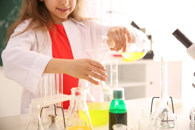 Photo of Schoolchild making experiment at table in chemistry class, closeup