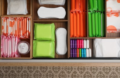 Photo of Storage of different feminine hygiene products in wooden drawer, top view