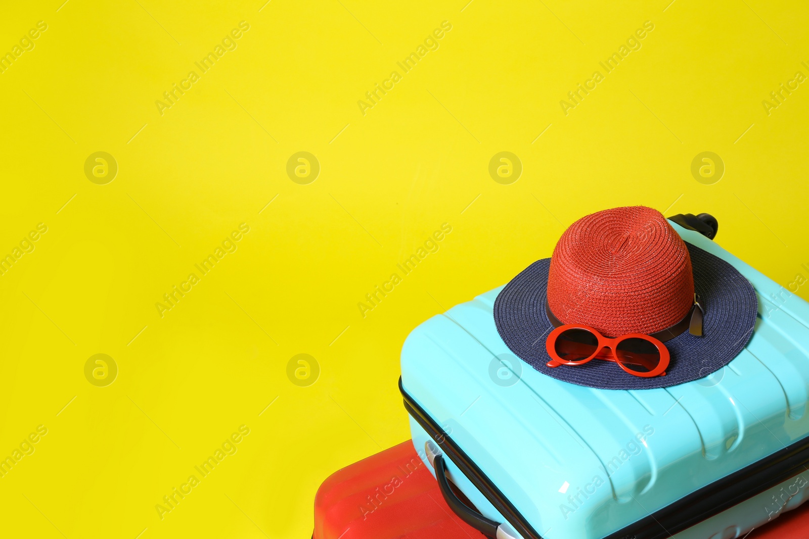 Photo of Stylish suitcases and beach accessories on yellow background. Space for text