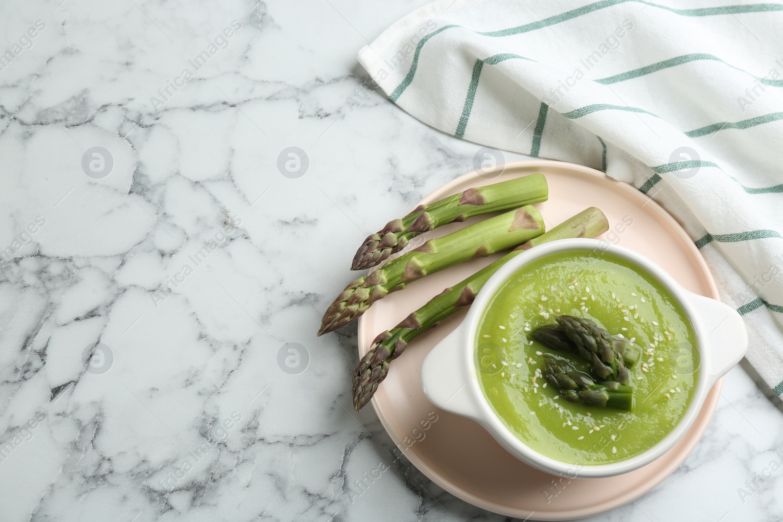 Photo of Delicious asparagus soup served on white marble table, flat lay. Space for text