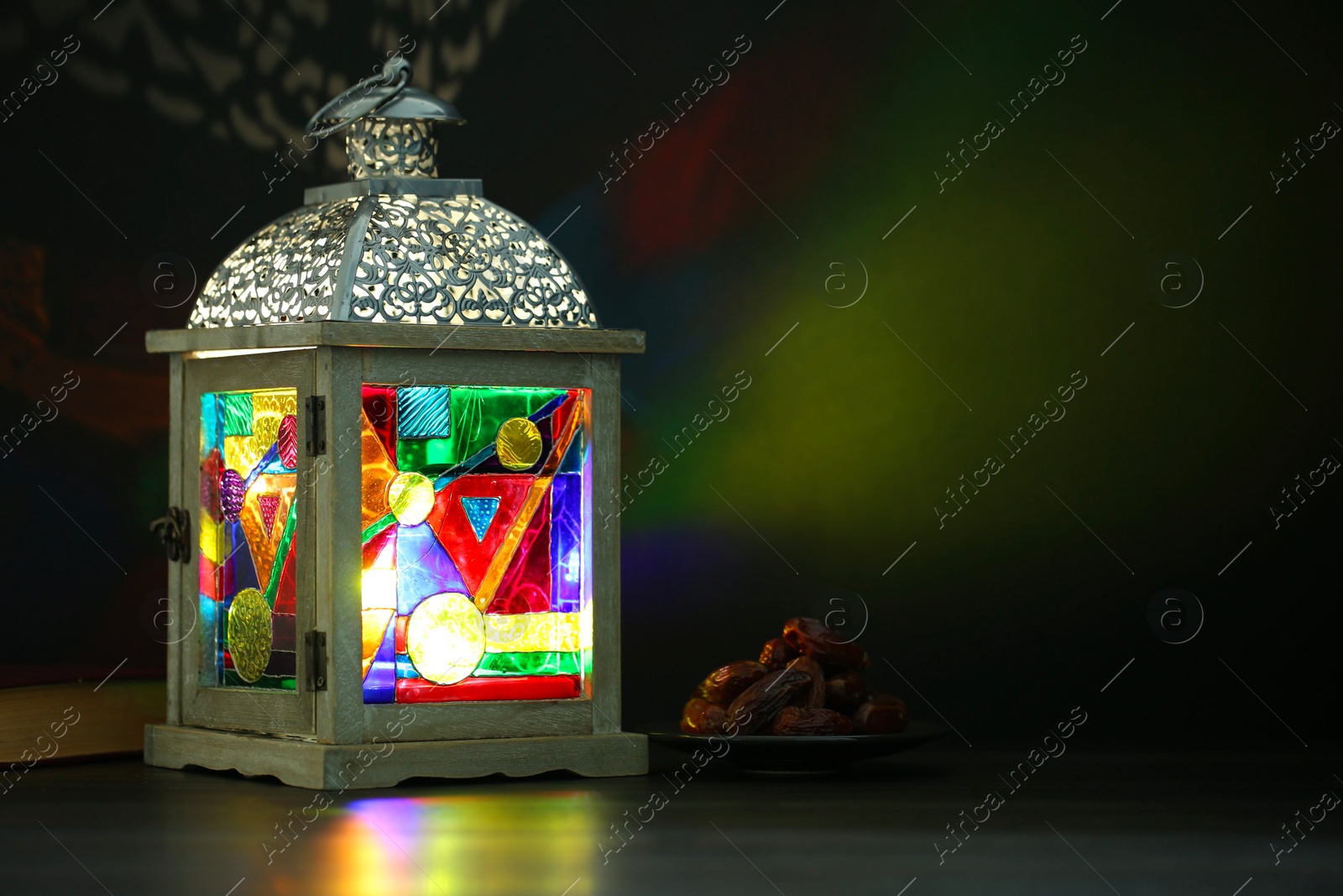 Photo of Decorative Arabic lantern on table against dark background. Space for text