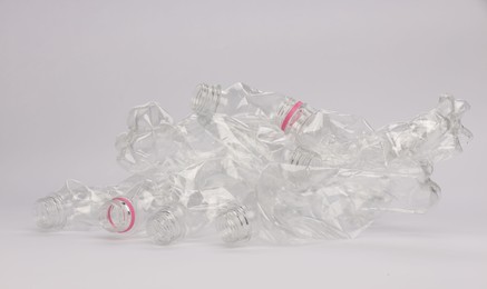 Photo of Crumpled disposable plastic bottles on white background