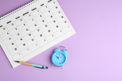 Photo of Calendar, pen and alarm clock on violet background, flat lay
