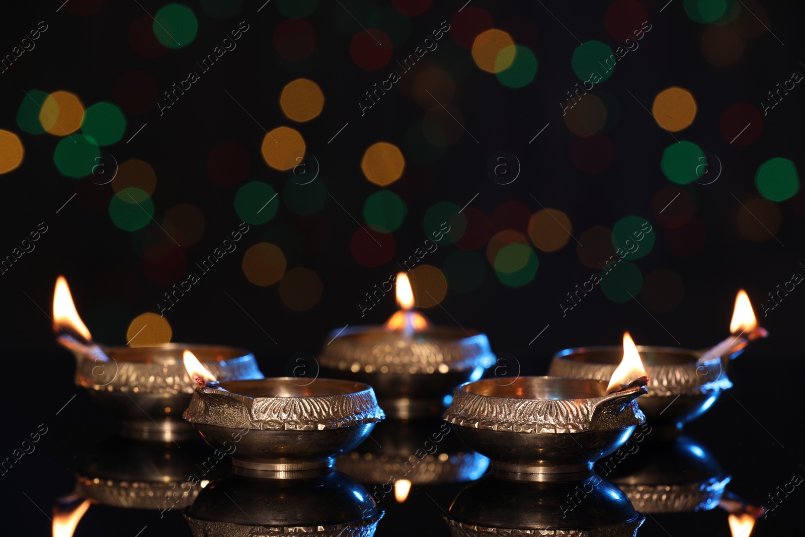 Photo of Many lit diyas on dark background with blurred lights, space for text. Diwali lamps