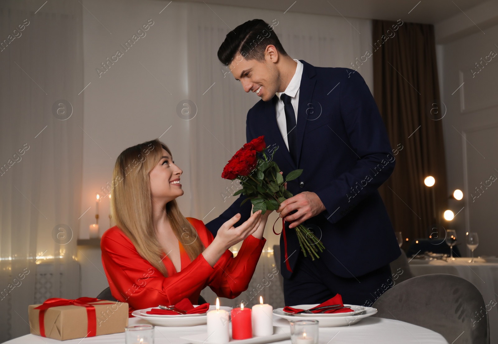 Photo of Man presenting roses to his beloved woman in restaurant at romantic dinner