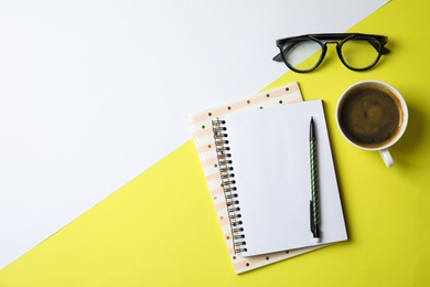 Notebooks, glasses and coffee on color background, top view with space for text