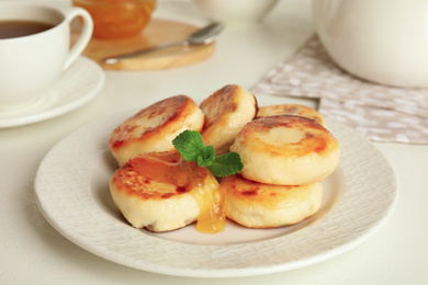 Photo of Delicious cottage cheese pancakes with mint on white table