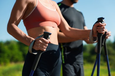 Couple practicing Nordic walking with poles outdoors on sunny day, closeup