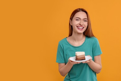 Young woman with piece of tasty cake on orange background, space for text