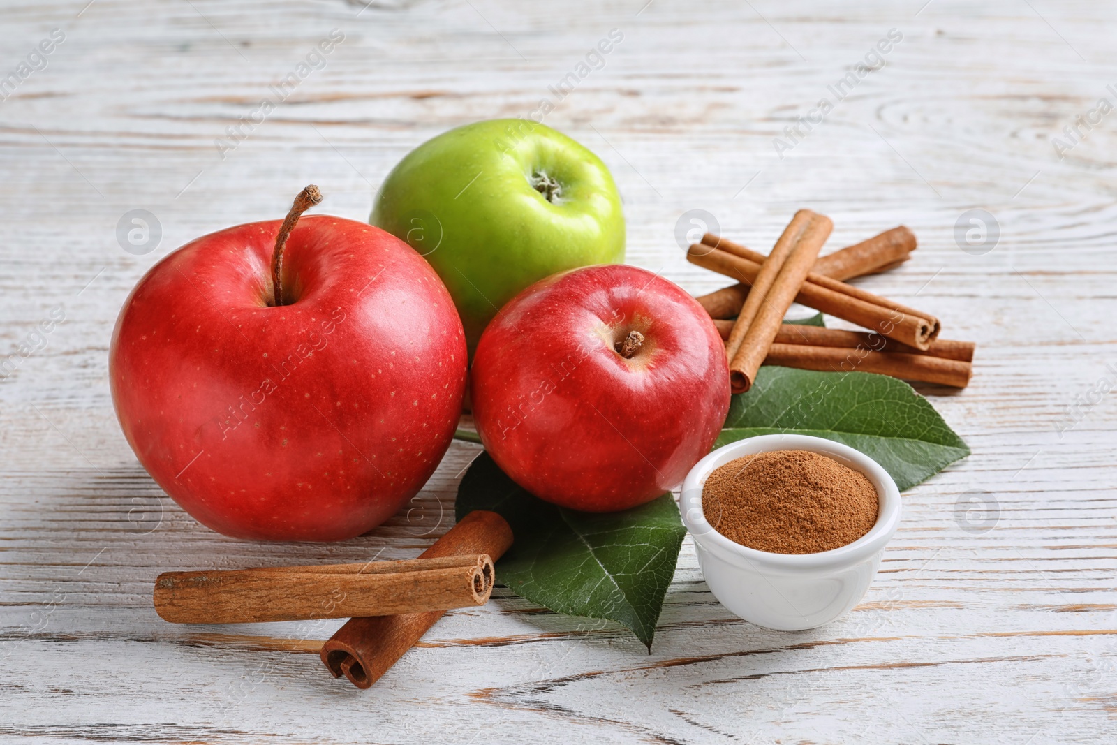 Photo of Fresh apples with cinnamon sticks and powder on wooden table