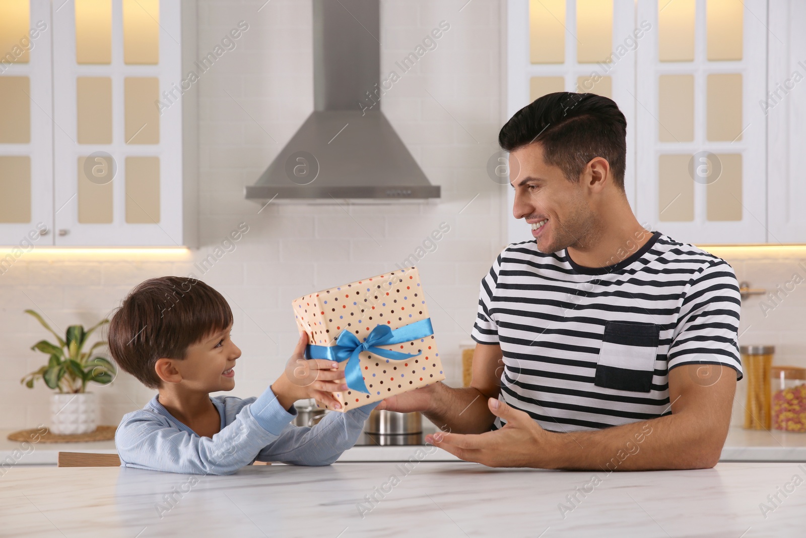 Photo of Man receiving gift for Father's Day from his son in kitchen