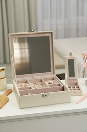 Photo of Elegant jewelry box with beautiful bijouterie on dressing table in bedroom