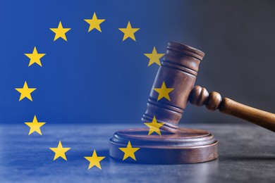 Image of Double exposure of European union flag and judge's gavel on grey table