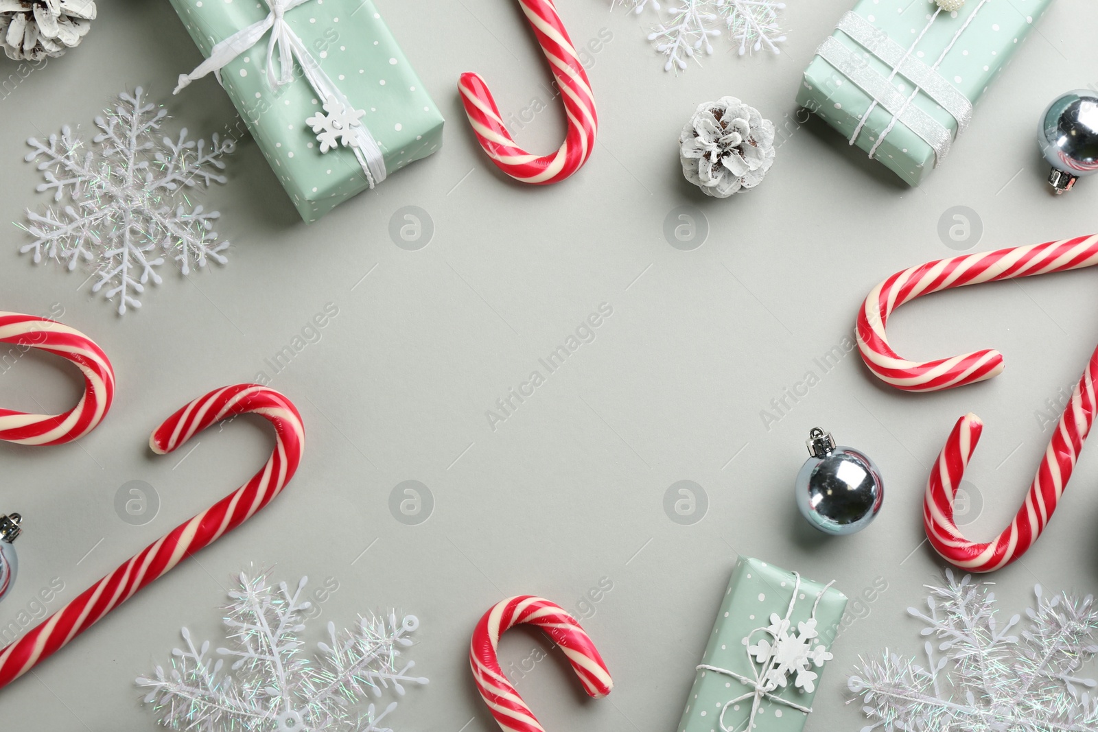 Photo of Frame of candy canes and Christmas decor on grey background, flat lay. Space for text