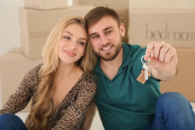 Young couple with key from their new house indoors, closeup