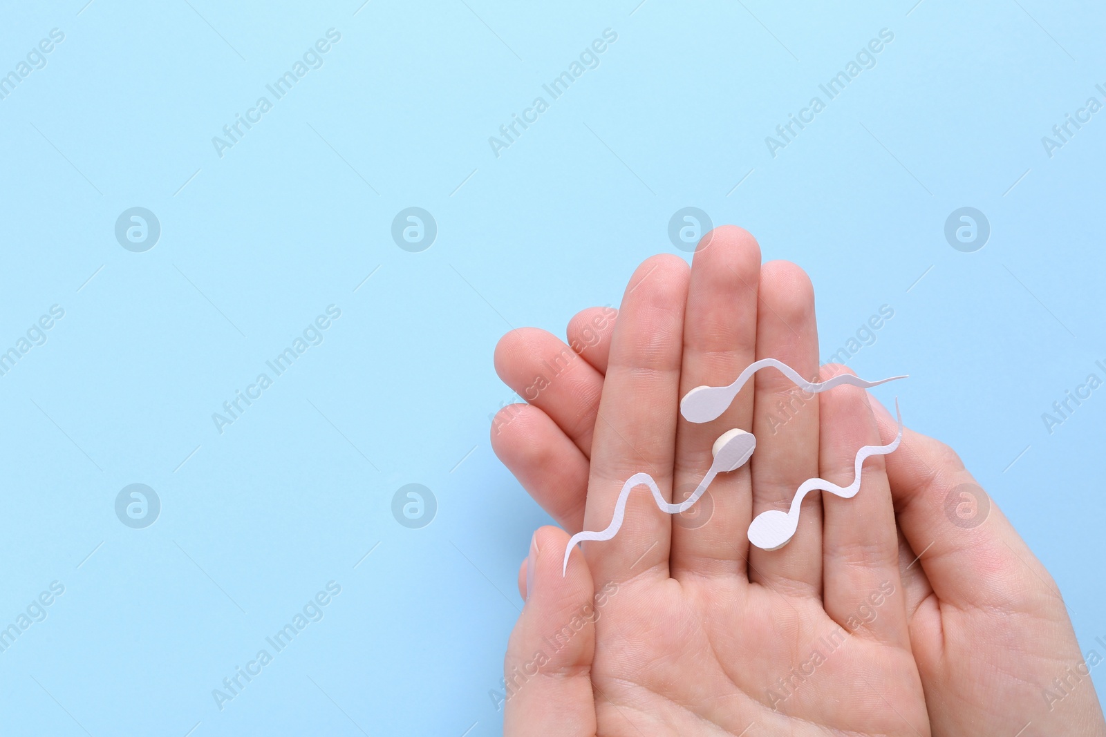 Photo of Reproductive medicine. Woman holding figures of sperm cells on light blue background, top view with space for text