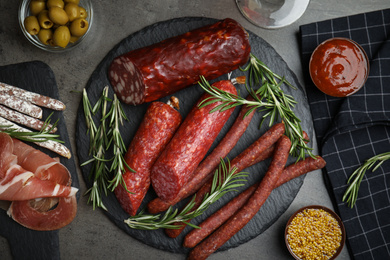 Photo of Different types of sausages served on grey table, flat lay