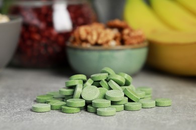 Pile of pills near foodstuff on grey table, closeup. Prebiotic supplements