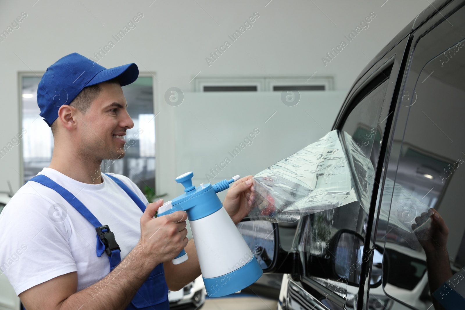 Photo of Worker tinting car window with foil in workshop