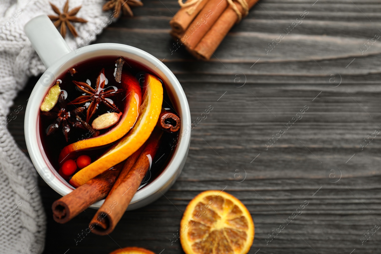 Photo of Cup of tasty mulled wine on black wooden table, flat lay. Space for text