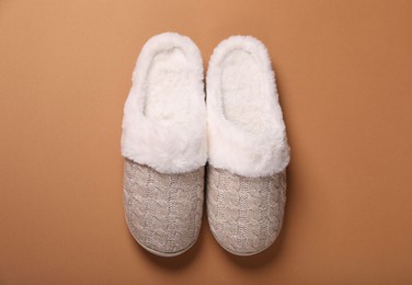 Photo of Pair of beautiful soft slippers on light brown background, top view