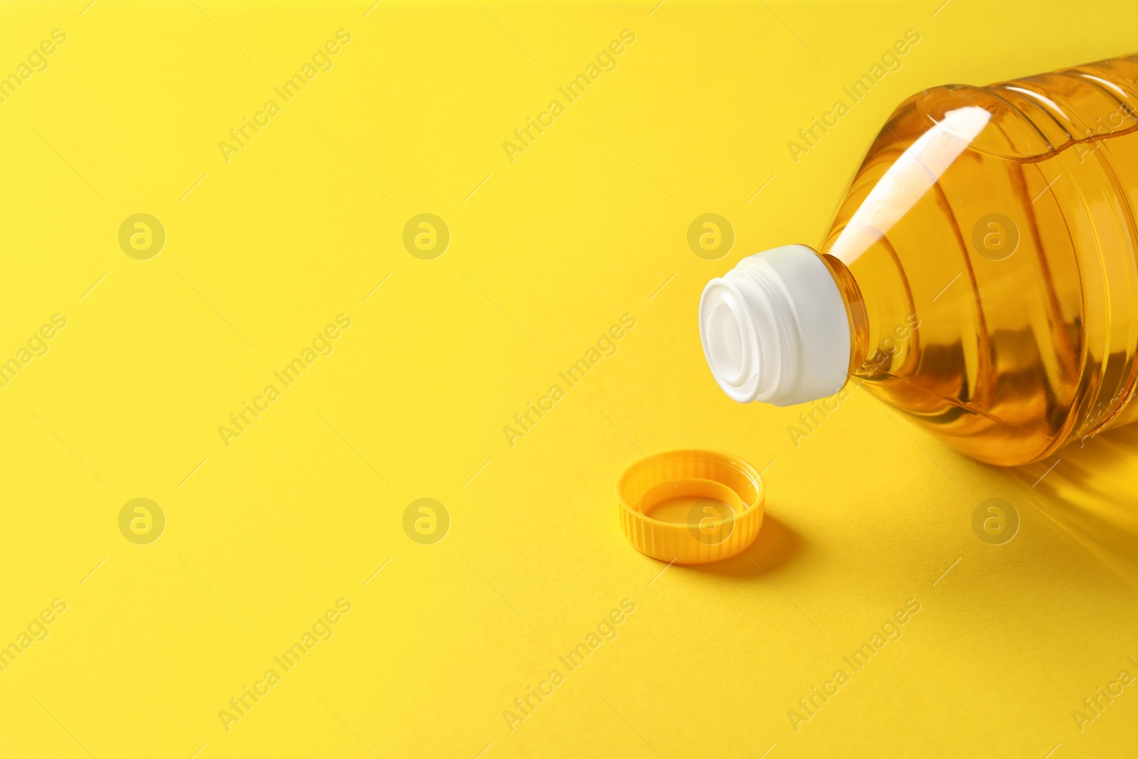 Photo of Plastic bottle of cooking oil on yellow background. Space for text