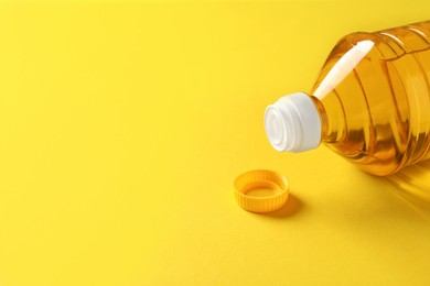 Photo of Plastic bottle of cooking oil on yellow background. Space for text