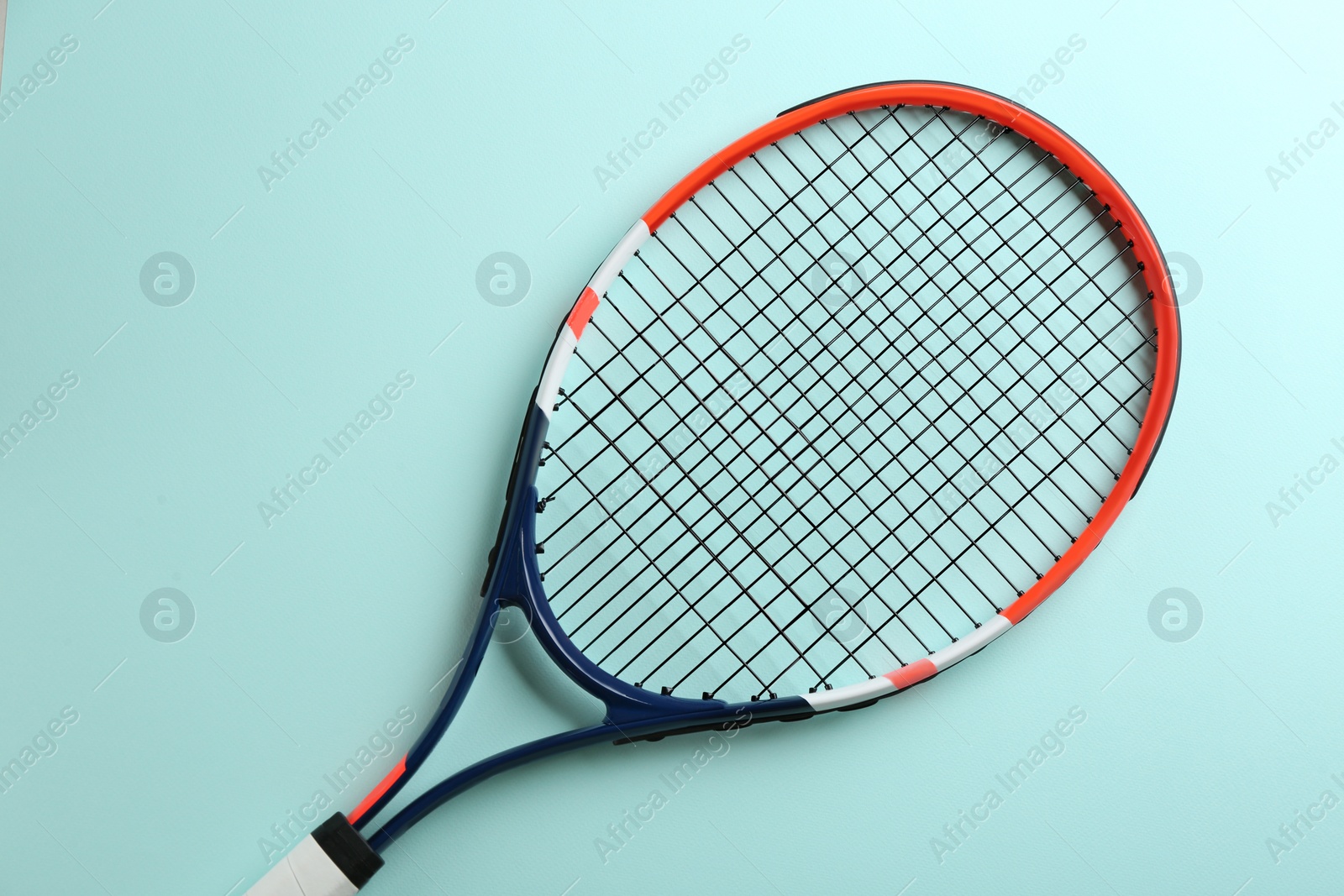 Photo of Tennis racket on light blue background, top view. Sports equipment