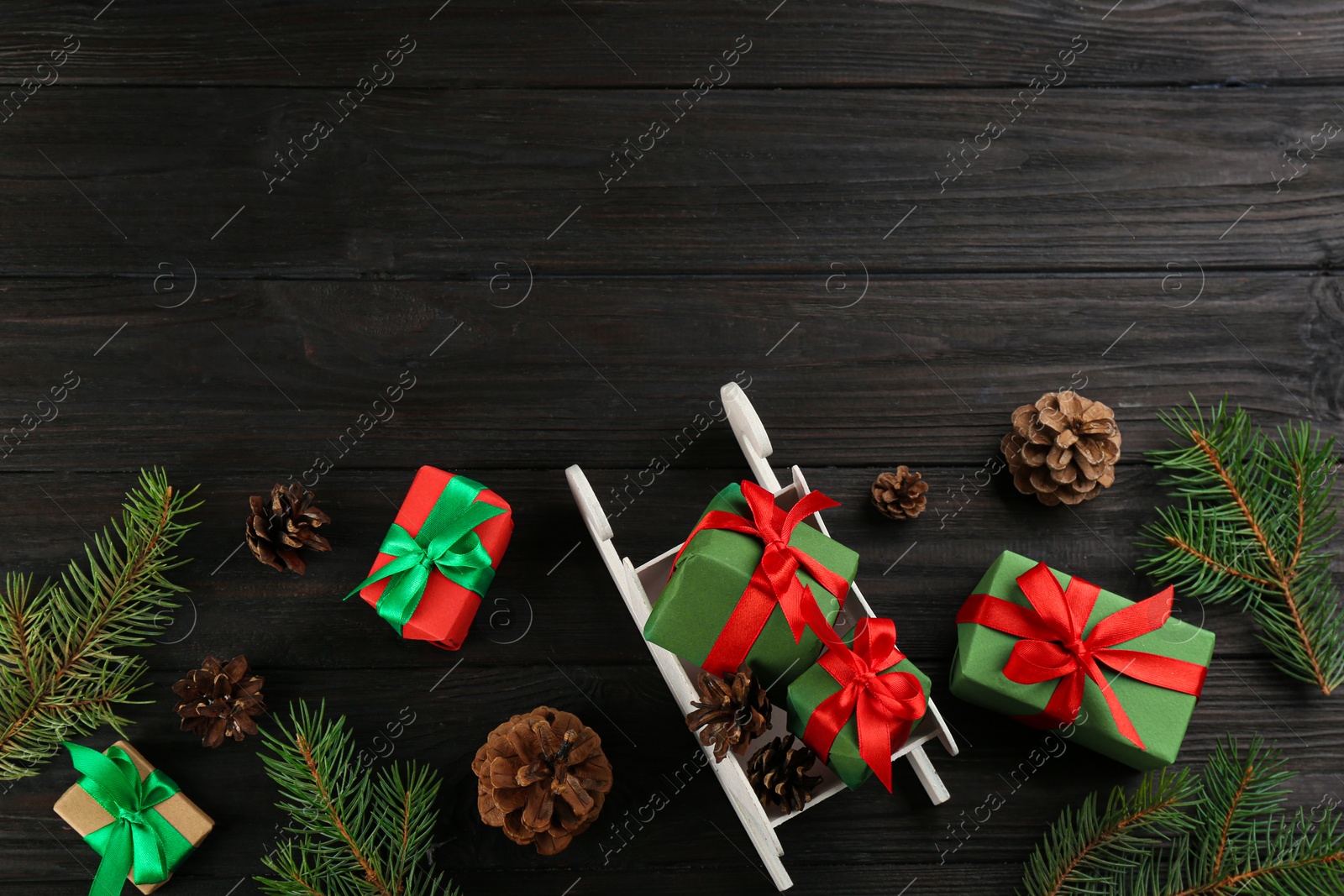 Photo of Beautiful Christmas composition with miniature sleigh on black wooden table, flat lay. Space for text