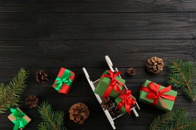 Photo of Beautiful Christmas composition with miniature sleigh on black wooden table, flat lay. Space for text