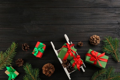 Beautiful Christmas composition with miniature sleigh on black wooden table, flat lay. Space for text