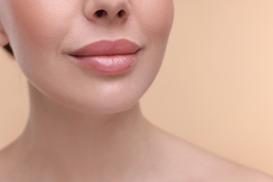 Woman with beautiful lips on beige background, closeup