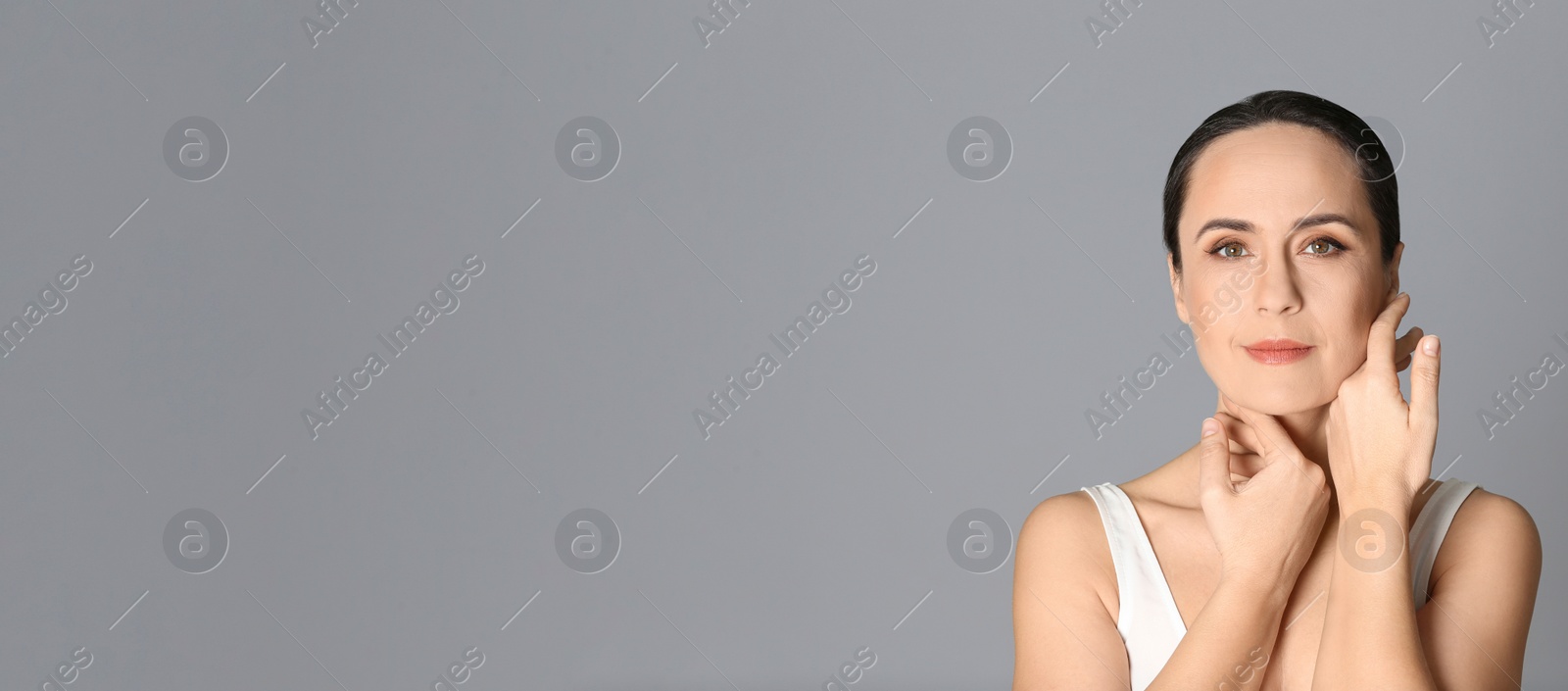 Image of Portrait of beautiful mature woman on grey background, space for text. Banner design