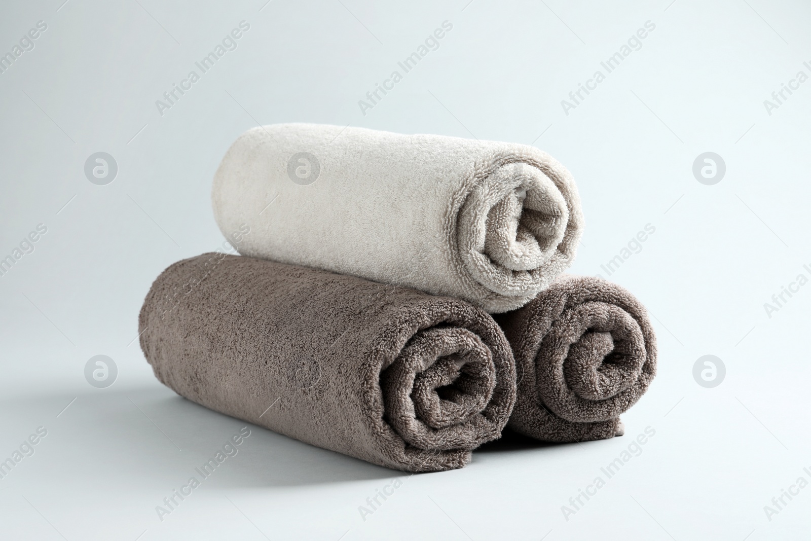 Photo of Fresh fluffy rolled towels on grey background