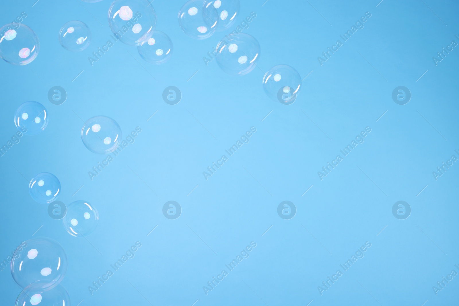 Photo of Many beautiful soap bubbles on light blue background. Space for text