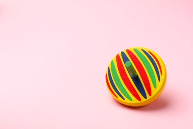 Photo of One colorful spinning top on pink background, space for text