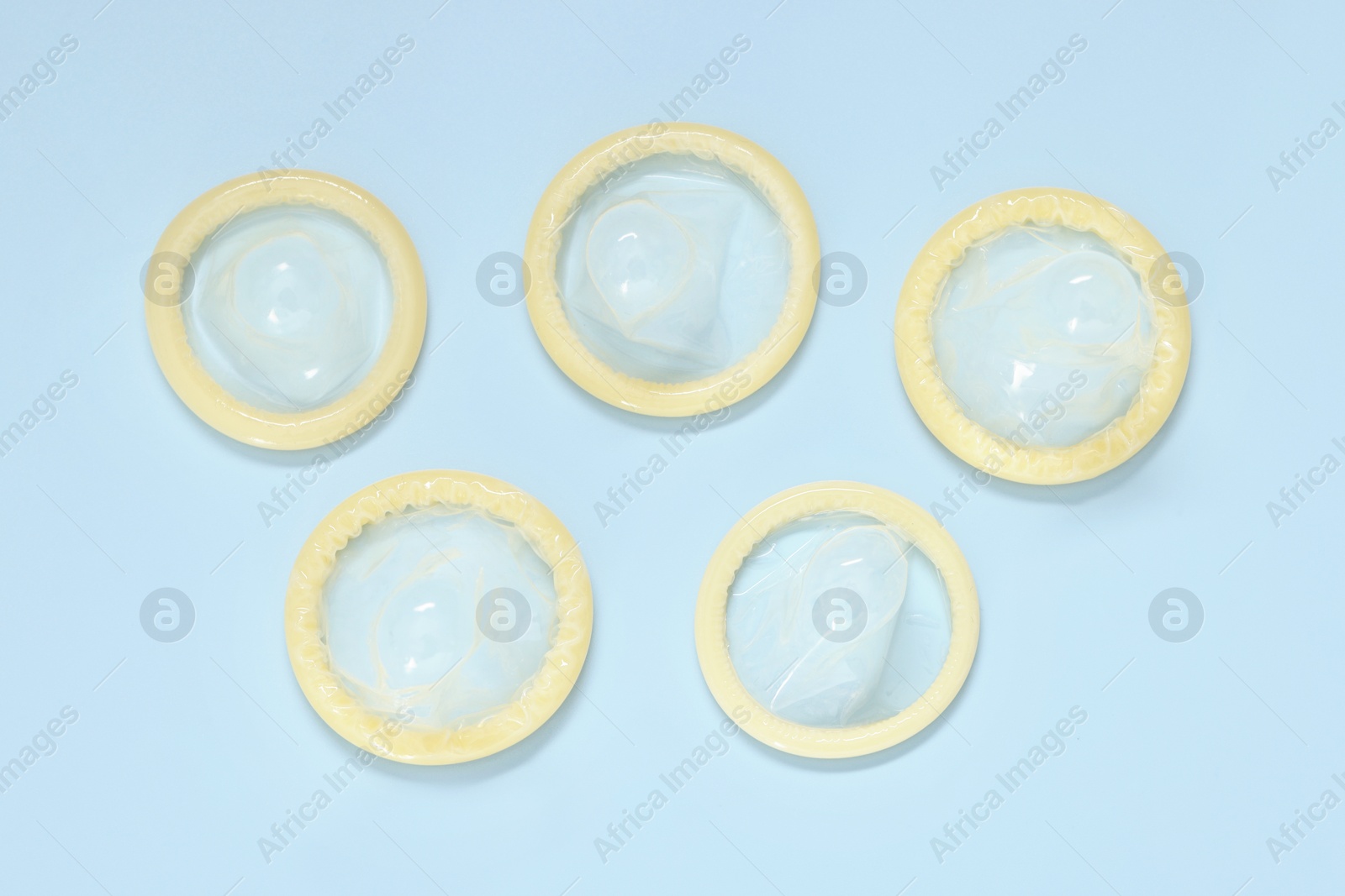 Photo of Condoms on light blue background, top view. Safe sex