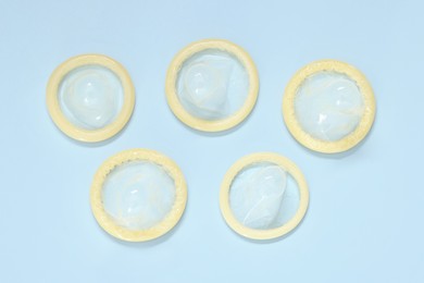 Photo of Condoms on light blue background, top view. Safe sex