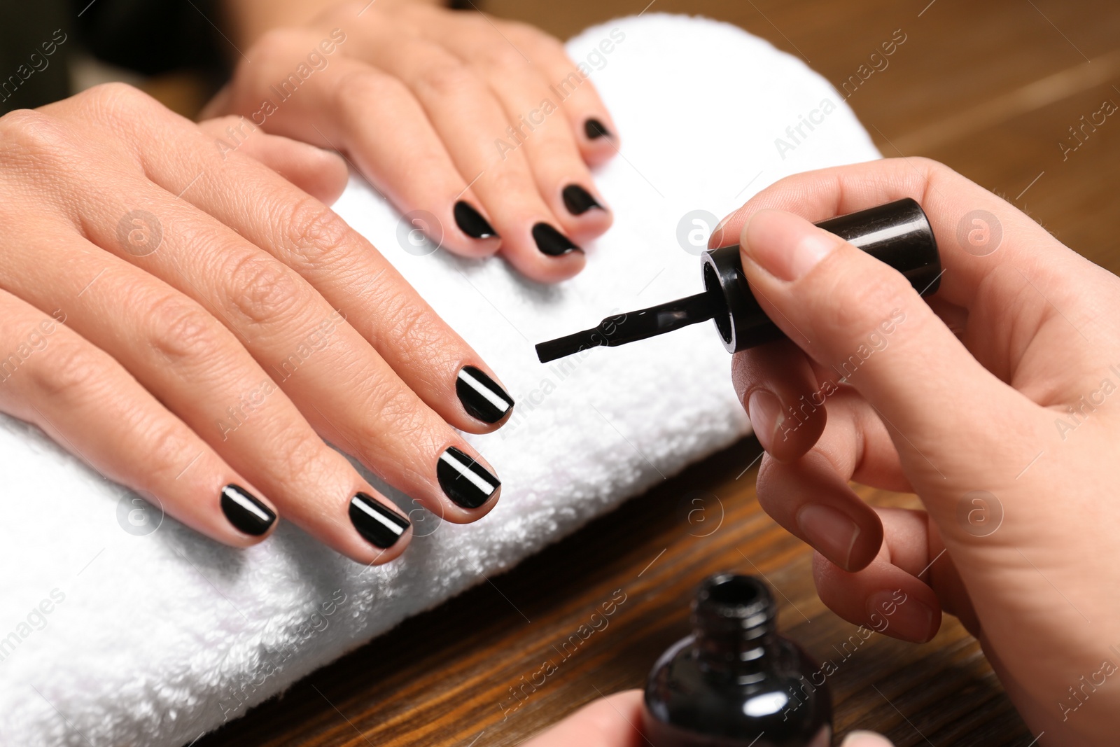 Photo of Manicurist painting client's nails with polish in salon, closeup