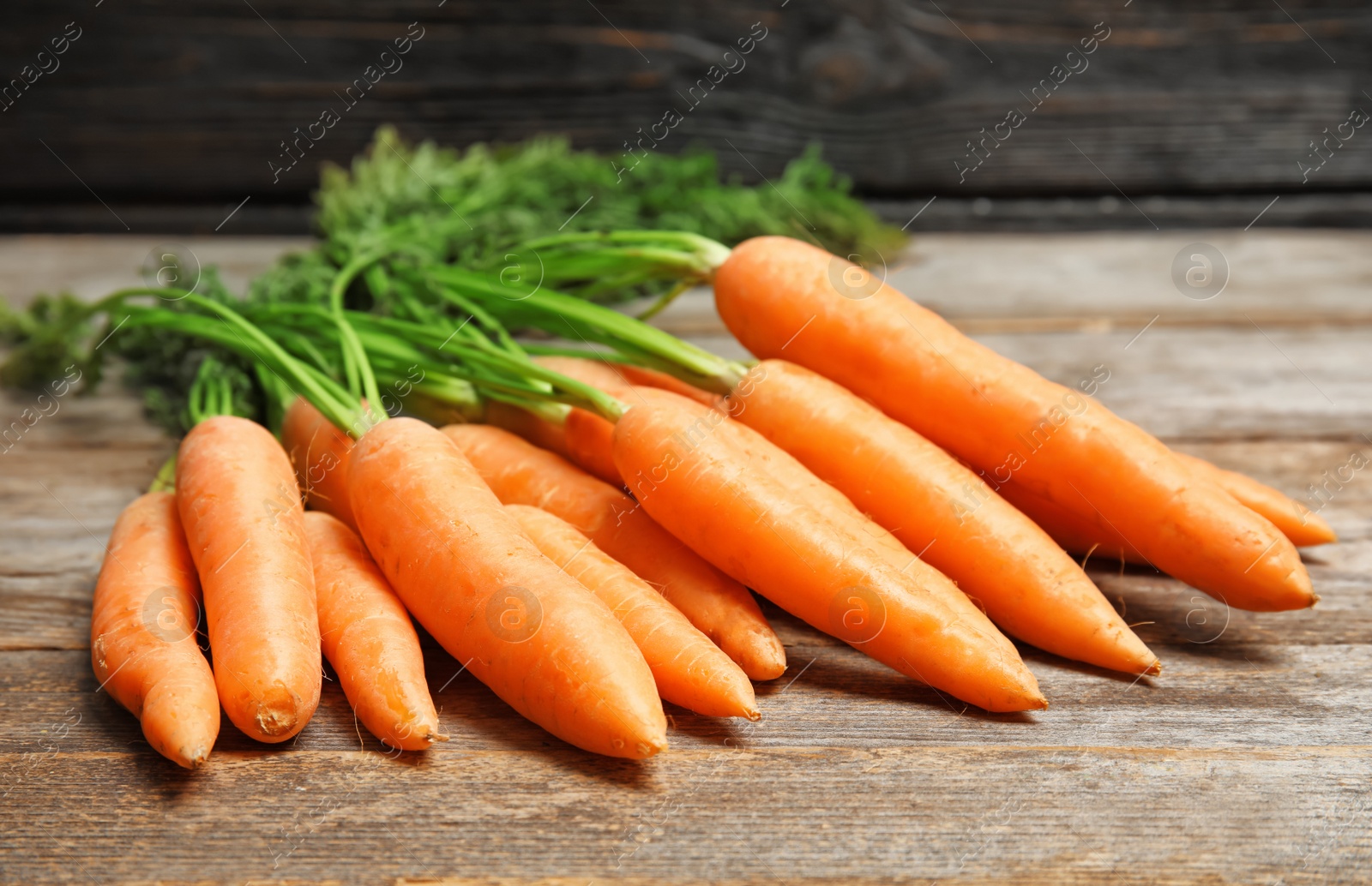 Photo of Ripe carrots on wooden table. Healthy diet