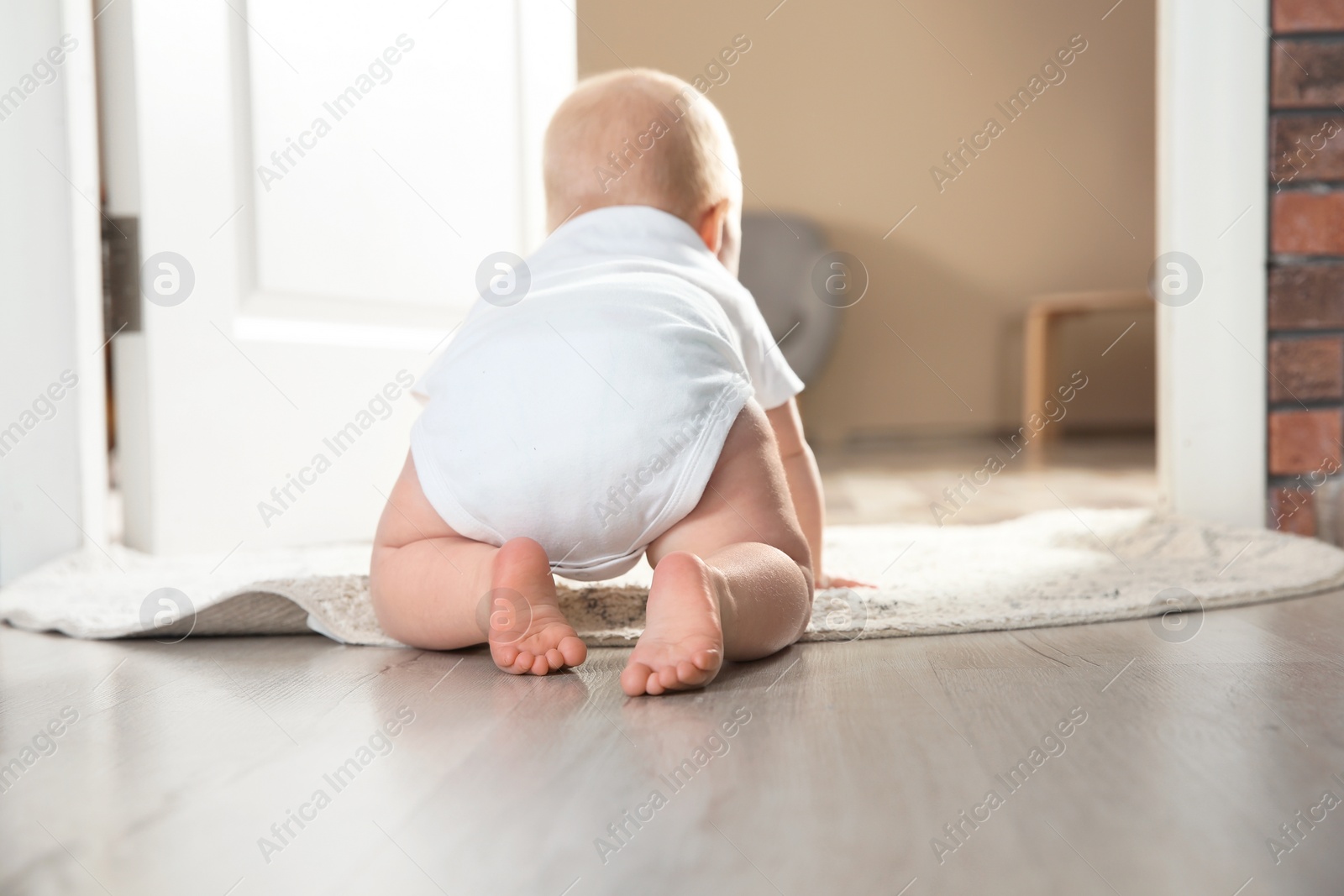 Photo of Cute little baby crawling on rug indoors