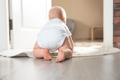 Photo of Cute little baby crawling on rug indoors