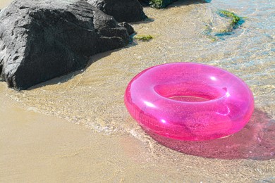 Photo of Bright inflatable ring on sandy beach near sea. Space for text