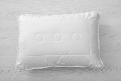 Soft bed pillow on wooden background, top view