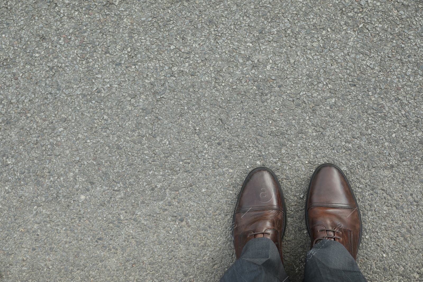 Photo of Man in brown shoes standing on asphalt, top view. Space for text